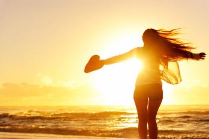 Kvinde på strand nyder solnedgang