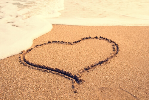 Et hjerte tegnet i sandet ved et hav