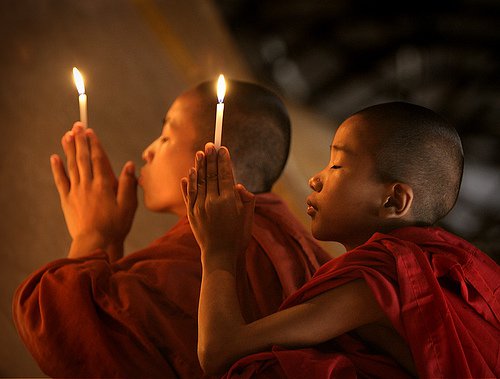 Buddhistiske børn beder med lys