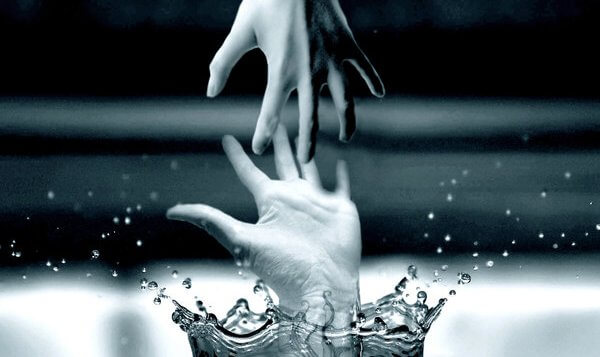 Hånd rækker ud efter anden hånd, der er ved at drukne