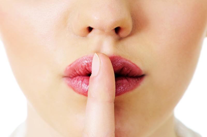 Kvinde giver tegn til at være stille med finger for munden