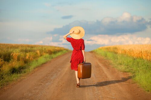 Kvinde med hat og kuffert går på vej for at glemme sin fortid