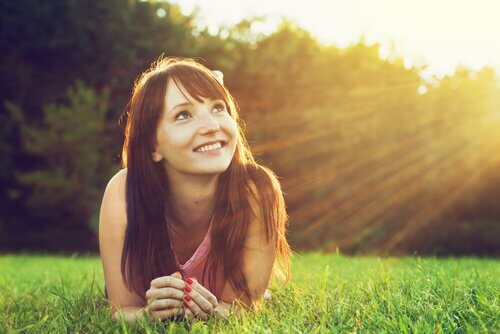 Kvinde på græs smiler på grund af positiv psykologi