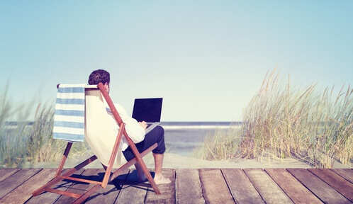 Mand med computer på strand arbejder ifølge Pareto-princippet