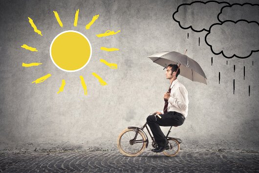 Mand på cykel følger positiv psykologi og kører fra regn til solskin