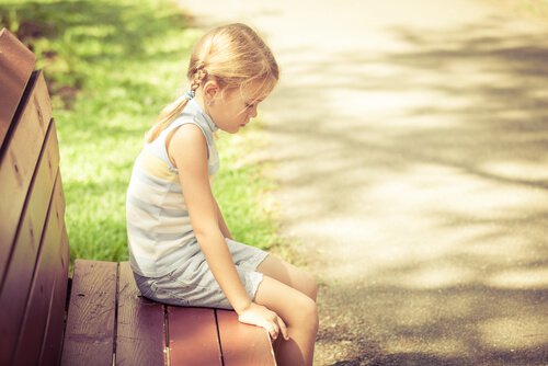 En trist pige alene på en bænk