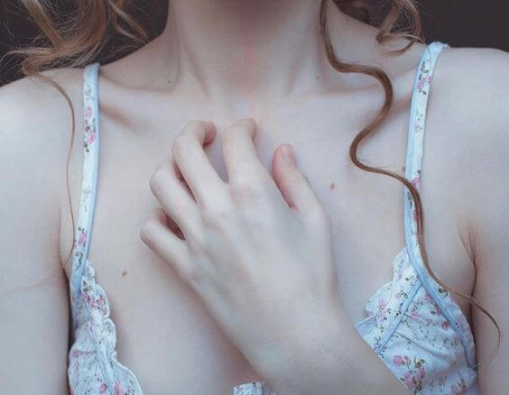 Kvinde lægger hånd på hjerte for at illustrere, at man kan blive syge af undertrykte følelser