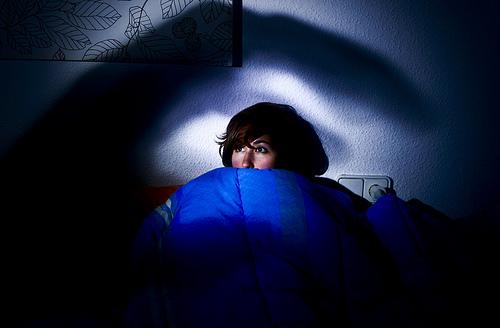Skræmt kvinde i en seng symboliserer søvnlammelse