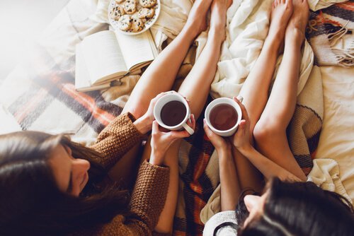 To piger drikker te i seng for at give hinanden social støtte