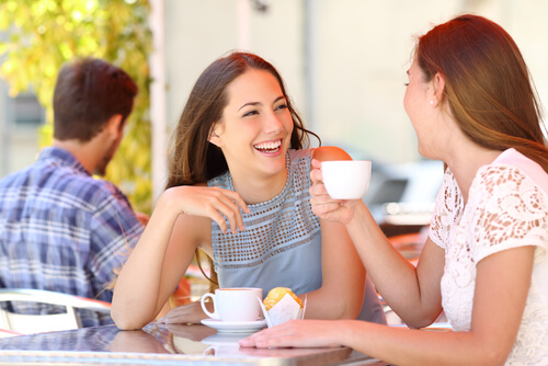 To veninder drikker kaffe sammen, griner og drager nytte af sociale evner
