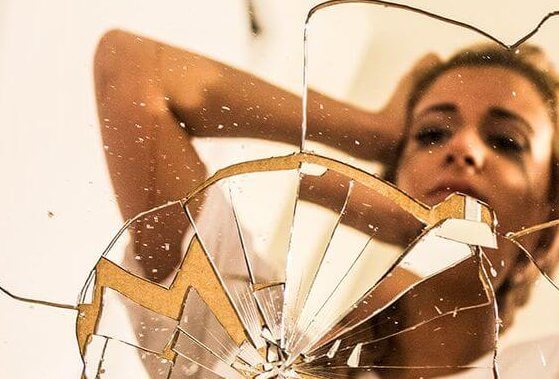 Kvinde foran ødelagt spejl, som hun har smadret på grund af et panikanfald