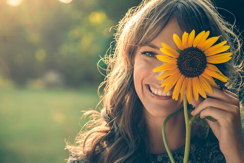 Smilende kvinde tager blomst op foran øjet