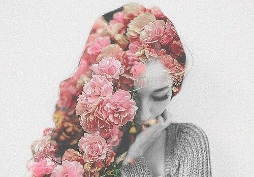 Kvinde med lyserøde blomster i håret viser, hvordan sanser påvirker følelser, da hun bliver berørt at blomsternes duft og farve