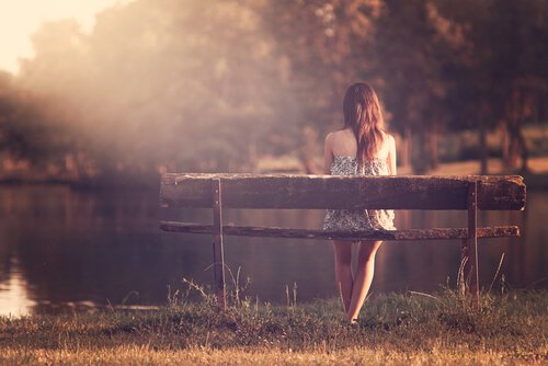 En intelligent kvinde nyder tid alene på en bænk ved en sø