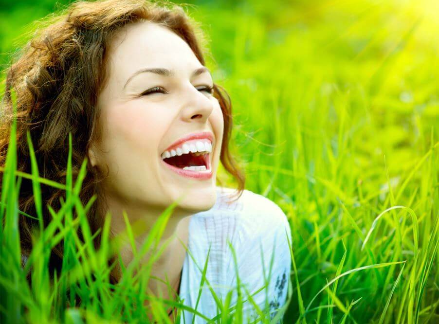 Glad kvinde smiler på græsmark