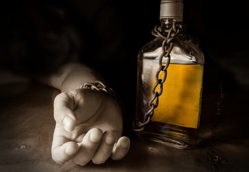 Hånd er lænket til flaske som symbol for alkoholisme