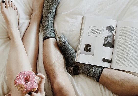 Pars ben i seng med bog og donut