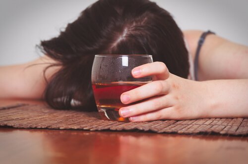 Kvinde med glas i håndet er faldet i søvn på grund af alkoholisme