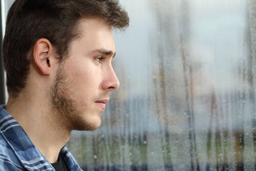 Trist mand kigger ud af vindue i sorg over at skuffe familien