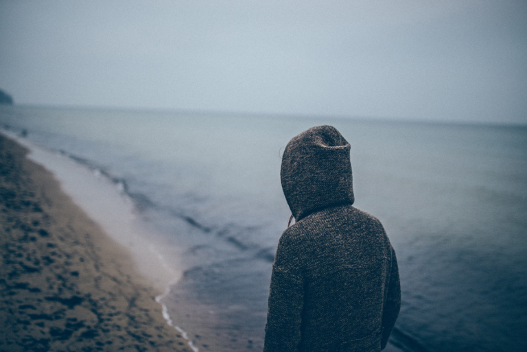 Deprimeret kvinde på strand er trist på grund af dysthymi