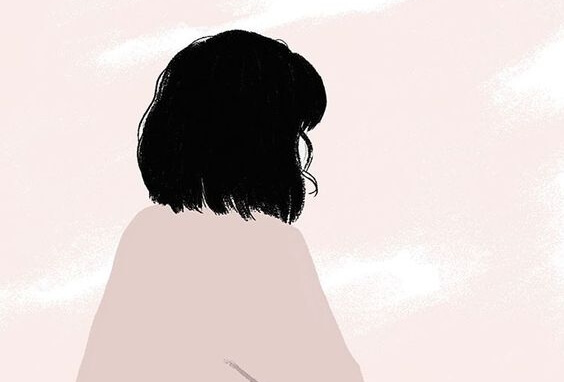 Kvinde i lyserød trøje sidder med ryg mod kamera