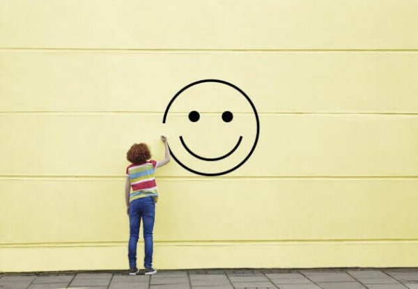 Person tegner smiley på væg