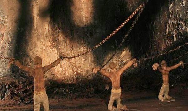 Mænd sidder lænket i Platons grotte