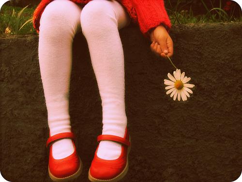 Barn sidder med blomst