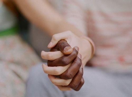 Par holder i hånd og viser kærtegn