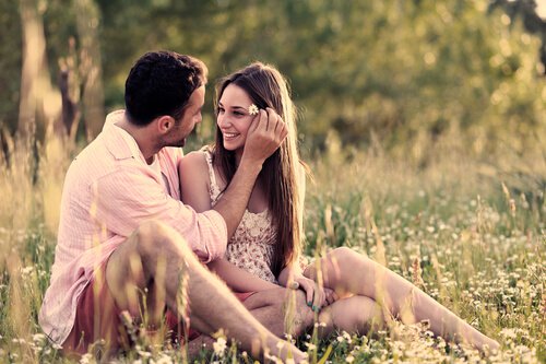 Forelsket par sidder på eng og nyder sensommer kærlighed