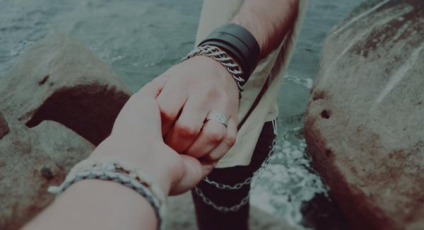 Personer holder i hånd foran hav