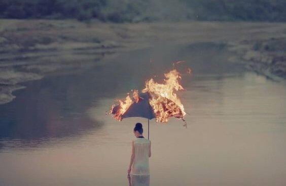 Kvinde står foran sø med brændende paraply
