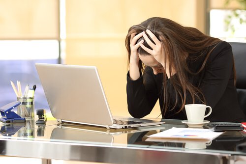Kvinde på kontor tager sig til hovedet, da hun oplever chikane på arbejdspladsen