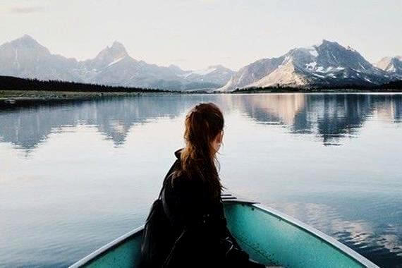 Pige på båd foran bjerge