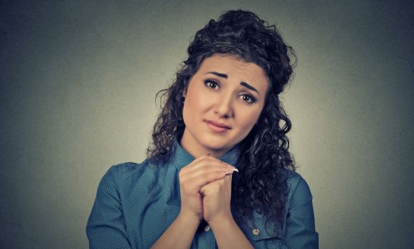 Kvinde med hænderne knuget vil bed eom ting med et blik