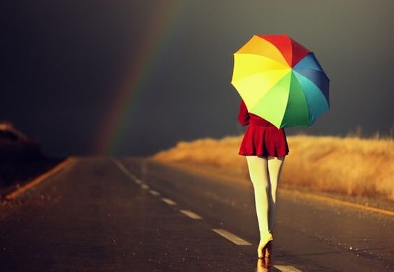 Kvinde med paraply går mod regnbue