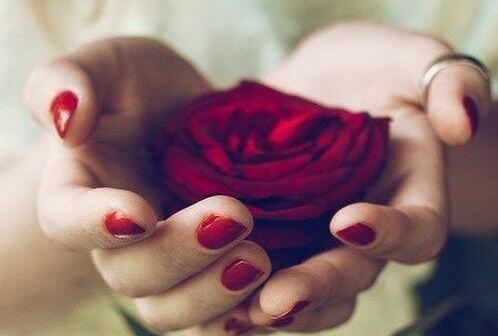 Kvinde holder rose i hånden