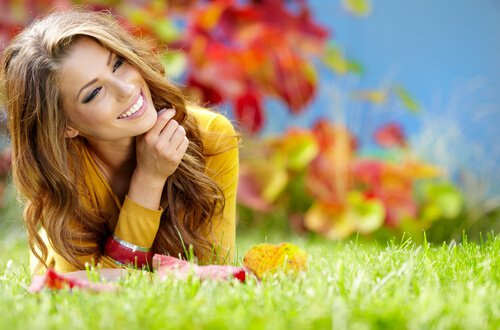 Kvinde på græs smiler og er glad på grund af mindfulness