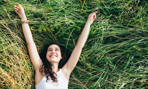 Smilende kvinde i græs lever et simpelt liv