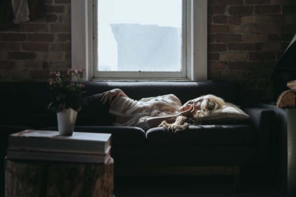 Kvinde sover på sofa og viser, hvordan følelser påvirker vores krop gennem psykosomatiske lidelser