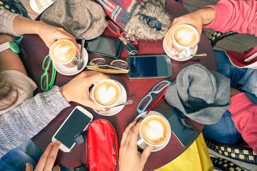 Venner drikker kaffe med mobilet liggende på bordet