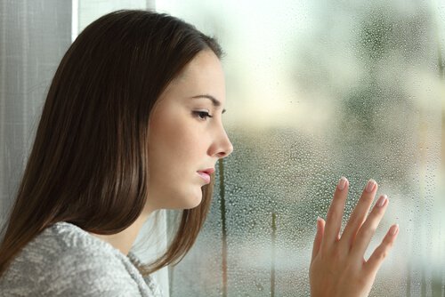Trist kvinde ved vindue efter ødelagt forhold