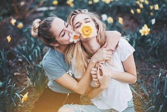 Fordele ved venner er, at man kan være sig selv, som disse to piger med blomster i munden