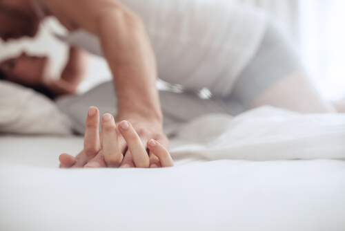 Par i seng holder hænder og er ved at ligge og putte
