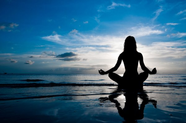 Kvinde mediterer ved vand og er igang med mindfulness