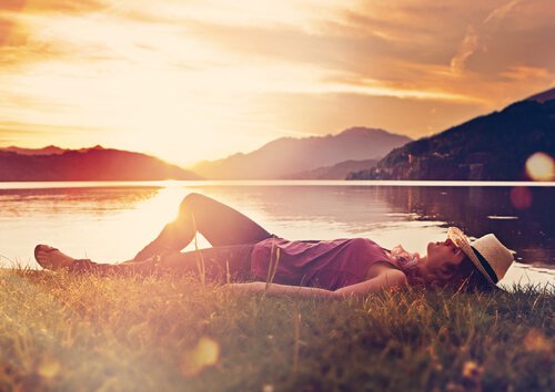 Kvinde sover foran sø og bjerge