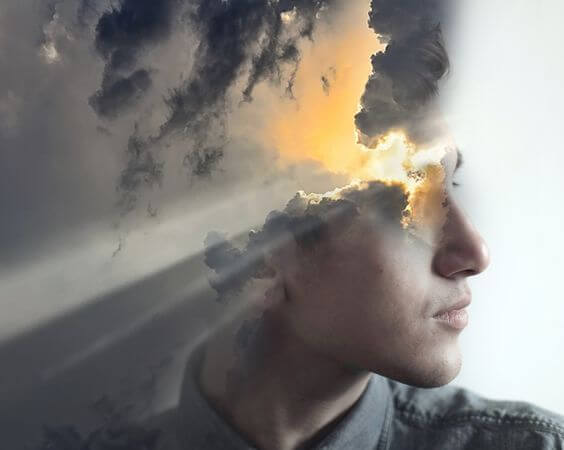 Mands ansigt, hvor solen bryder igennem skyer, ønsker at sabotere sig selv