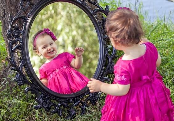 Pige med selvsikkerhed smiler til sig selv i spejl