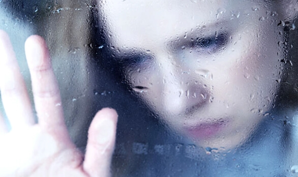 Kvinde ved vindue er trist på grund af overdrevet romantik