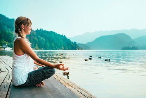 Kvinde dyrker yoga ved sø
